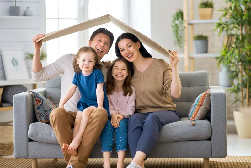 A family under a paper roof outline on their couch