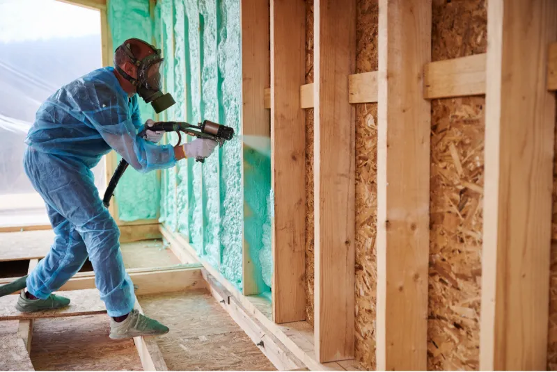 Installer in protective gear applying spray foam insulation